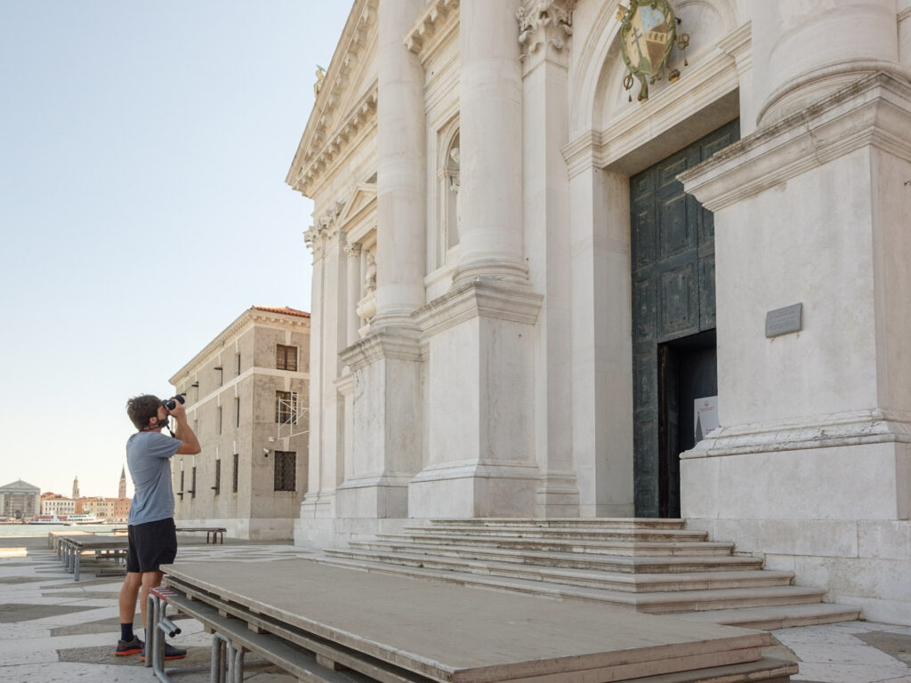 Un ragazzo fotografa la facciata della chiesa di San Giorgio Maggiore.